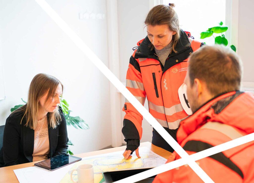 Tre personer i arbeidsklær som ser på plantegninger